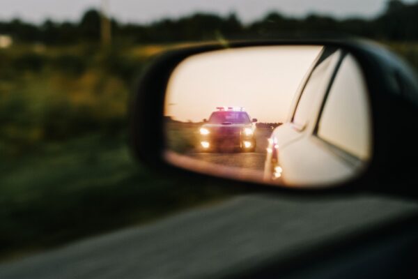 car mirror reflection showing police car with lights on