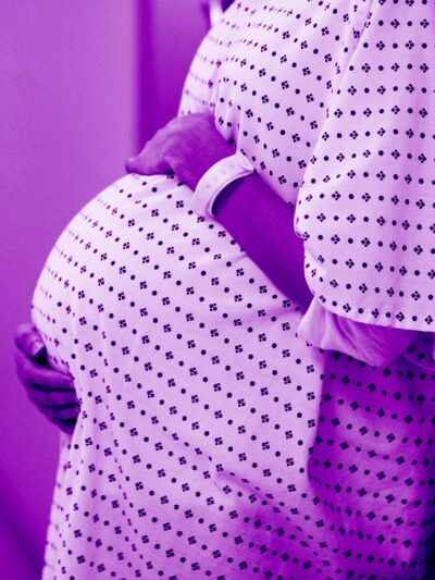pregnant woman in clinical setting wearing hospital gown