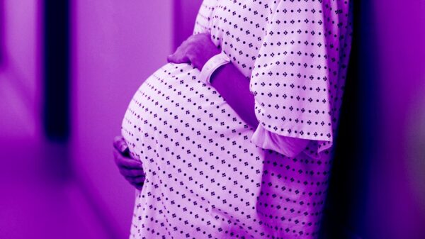 pregnant woman in clinical setting wearing hospital gown