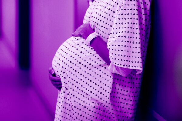 pregnant woman in clinical setting wearing hospital gown