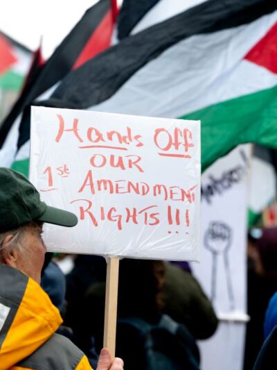 Protest sign reads "Hands Off our 1st Amendment Rights"
