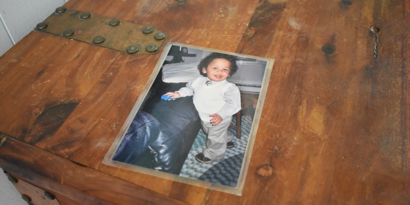 Photo of J.A. as a toddler dressed in a white suit